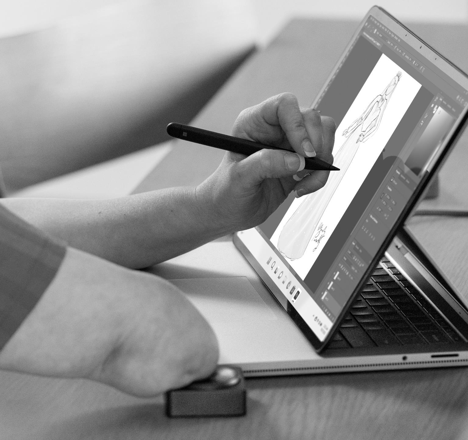 Person with one arm drawing a woman in a long dress on a laptop using a stylus.