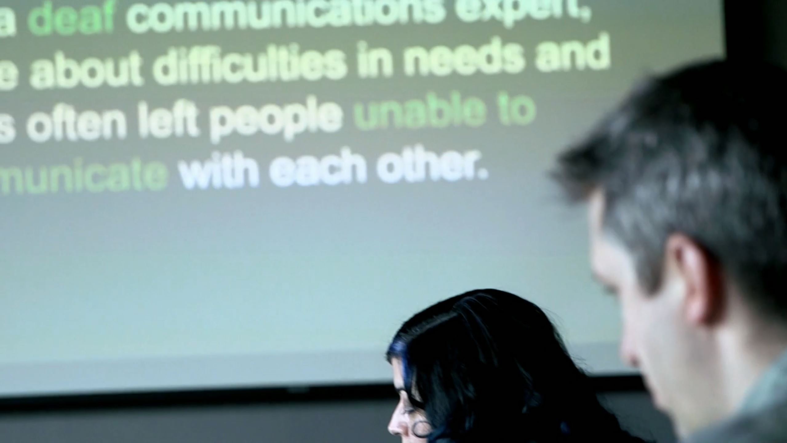 Two people watching a presentation on a projector.